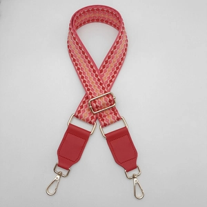 Dettaglio macro della tracolla intrecciata colorata con pelle PU rossa e ganci dorati