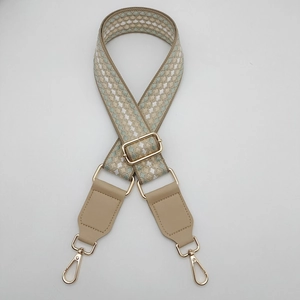 Dettaglio della tracolla in jacquard geometrico con pelle beige e moschettoni in metallo dorato