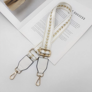 Détail de la bandoulière réglable en nylon blanc avec motif flèche dorée et crochets