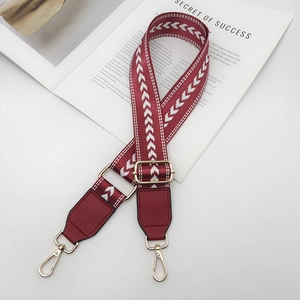 Détail de la bandoulière réglable en nylon bordeaux avec motifs chevrons et boucles dorées