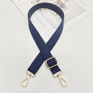 Détail d'une bandoulière réglable en nylon bleu marine avec des crochets en métal doré