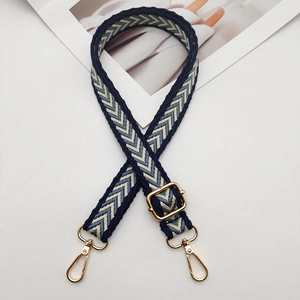 Detail of adjustable woven nylon strap with arrow pattern and gold metal hooks
