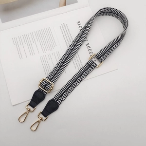 Adjustable black and white chevron shoulder strap with gold metal hooks and leather detail