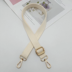 Détail de la bandoulière réglable en toile beige avec boucles en métal doré poli