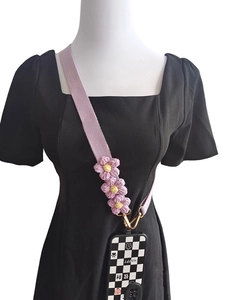 Detail of purple woven phone strap with 3D crochet flowers and checkered case