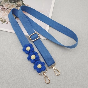 Detail of blue woven shoulder strap with handmade crochet daisy flowers and gold metal clips