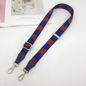 Macro detail of adjustable jacquard woven shoulder strap with polka dot pattern and metal clasp
