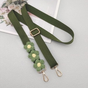 Detail view of army green woven crossbody strap with three yellow-centered crochet daisies