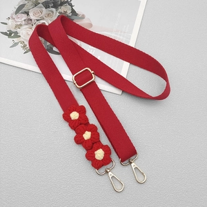 Detail of red woven bag strap featuring three 3D crochet flowers and gold hardware hooks