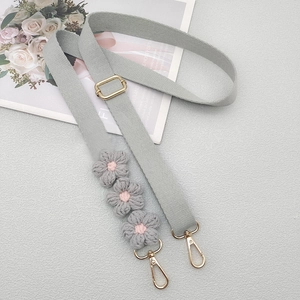 Close-up of adjustable grey woven shoulder strap with crochet flowers and gold lobster clasps