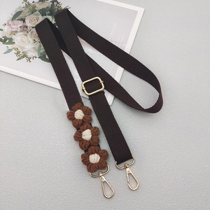 Detail of dark brown canvas bag strap with crochet flowers and gold metal lobster clasps