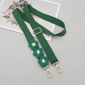 Adjustable green woven shoulder strap with knitted flower charms and gold metal hooks
