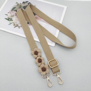 Close-up of khaki woven strap featuring handmade crochet daisy flowers and gold hardware