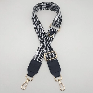 Detail of adjustable black and white herringbone woven shoulder strap with gold lobster clasps