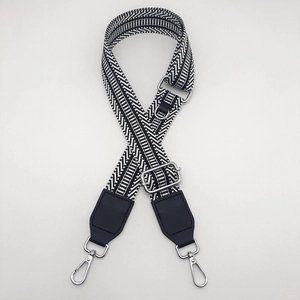 Detail of adjustable woven canvas strap with black and white patterns and silver metal hooks