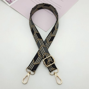 Detail view of geometric jacquard canvas purse strap with gold lobster clasps and buckle
