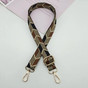 Detail view of woven adjustable bag strap with green geometric pattern and gold metal hooks