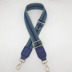 Macro detail of wave pattern canvas bag strap with gold metal hooks and D-ring