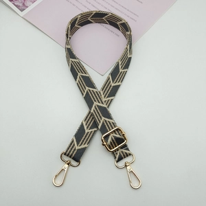 Close-up of geometric jacquard bag strap with golden metal hooks and adjustable buckle