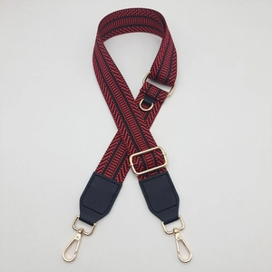 Detail of red and black geometric wave pattern wide canvas strap with gold metal hooks