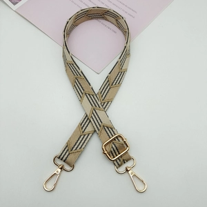 Close-up of wide canvas shoulder strap with beige V-shape geometric pattern and gold hardware