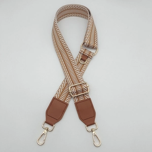 Detail of adjustable woven shoulder strap with brown chevron pattern and gold metal hooks