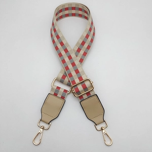 Close-up of adjustable woven shoulder strap with red plaid pattern and gold-tone metal hooks