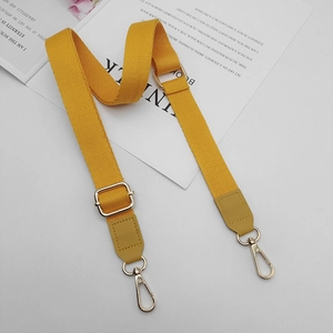 Detail of adjustable bright yellow cotton strap with gold metal hardware for handbags