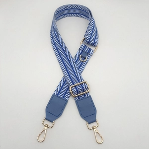 Close-up of blue and white striped woven shoulder strap with gold metal buckles