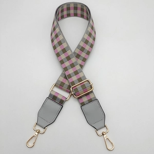 Detail of adjustable woven purse strap with colorful plaid pattern and gold lobster clasps