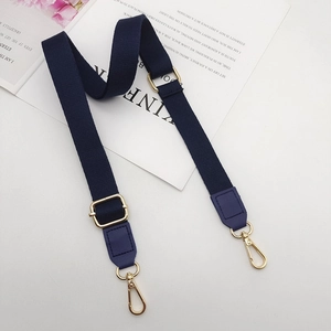 Detail view of navy blue cotton shoulder strap with gold metal buckle and leather ends
