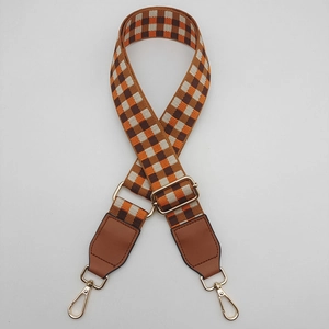 Close-up of wide braided bag strap with retro check pattern and gold metal buckles