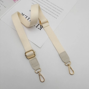 Adjustable beige cotton bag strap with light gray leather ends and gold metal hooks