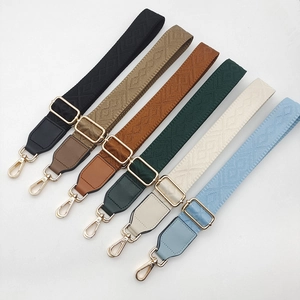 Detail of adjustable patterned bag straps with gold metal hooks and geometric texture