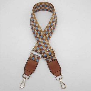 Close-up of woven adjustable shoulder strap with checkered pattern and gold metal hooks