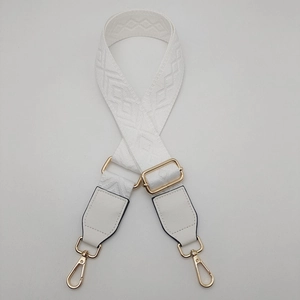 Detail of white wide adjustable crossbody bag strap with geometric jacquard and gold hooks