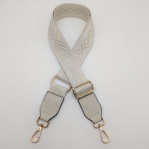 Detail of adjustable beige woven shoulder strap with gold-tone hardware and leather ends
