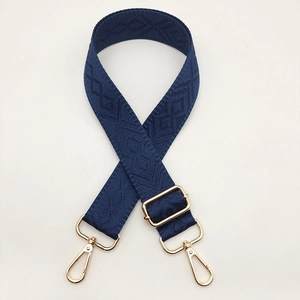 Detail view of navy blue diamond pattern woven shoulder strap with gold hardware