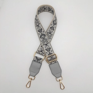 Detail of adjustable ethnic style bag strap with floral embroidery and gold metal hooks