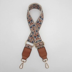 Detail view of ethnic floral embroidered wide bag strap with golden lobster clasps