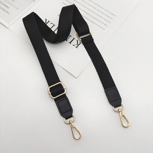 Detail view of adjustable black cotton strap with gold metal buckles and leather ends