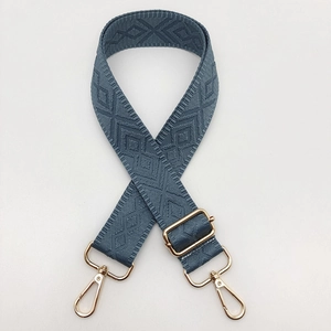 Detail of adjustable grey-blue woven shoulder strap with diamond pattern and gold metal hardware