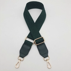 Detail of adjustable dark green woven strap with geometric patterns and gold metal buckle