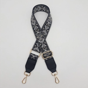 Detail of bohemian ethnic floral wide crossbody strap with gold metal hooks and leather
