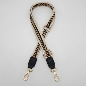 Detail of woven cross-body strap with black and gold V-pattern and gold hardware