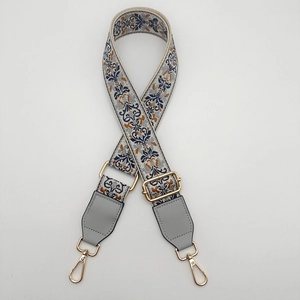 Close-up of ethnic embroidered bag strap with gold metal buckles and leather ends