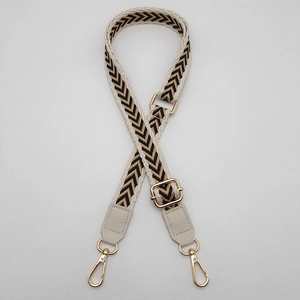 Detail of adjustable black and gold woven bag strap with beige PU leather and gold hooks