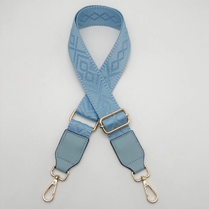 Detail of adjustable blue jacquard purse strap with gold metal hooks and leather joints