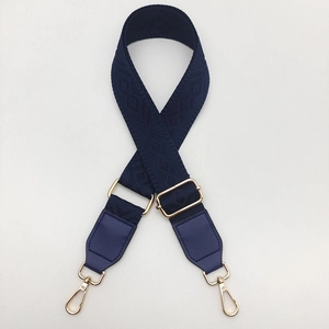 Close-up of dark blue woven bag strap with golden hardware and jacquard pattern