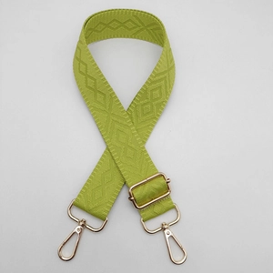 Detail of avocado green woven bag strap with diamond jacquard texture and gold hardware